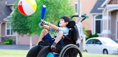 active boy in wheelchair with bat and ball