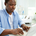 man in blue shirt using laptop